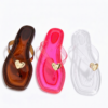 Display of Pink, Brown and Clear color of 3 Jelly Flat Trinidad and Tobago sandals on a white floor